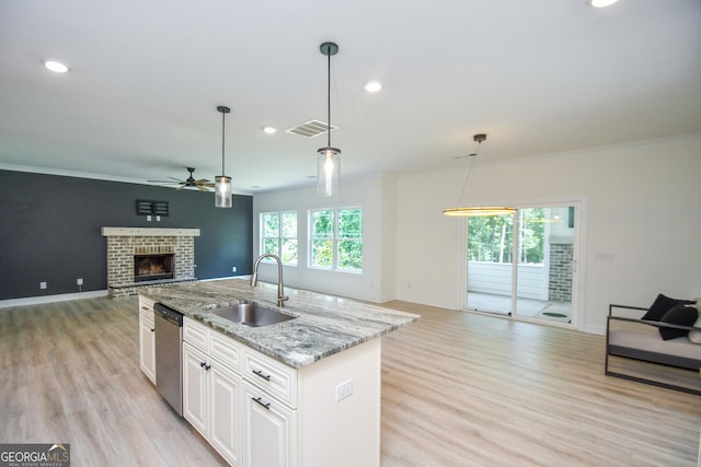 kitchen with white cabinets, a fireplace, light wood-type flooring, and sink