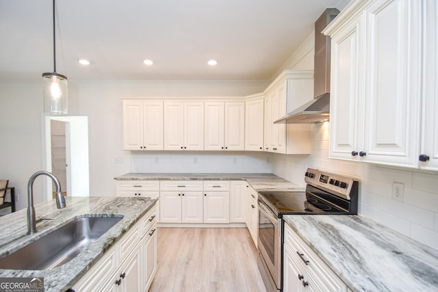 kitchen with stainless steel range with electric stovetop, light stone counters, light hardwood / wood-style floors, wall chimney exhaust hood, and sink