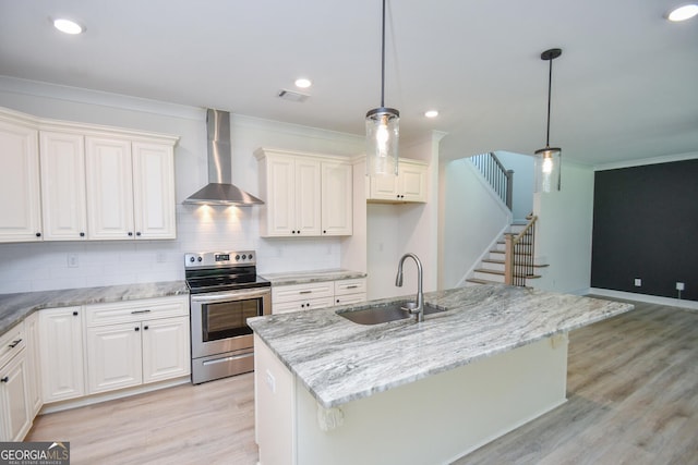 kitchen with pendant lighting, an island with sink, sink, wall chimney range hood, and stainless steel electric range