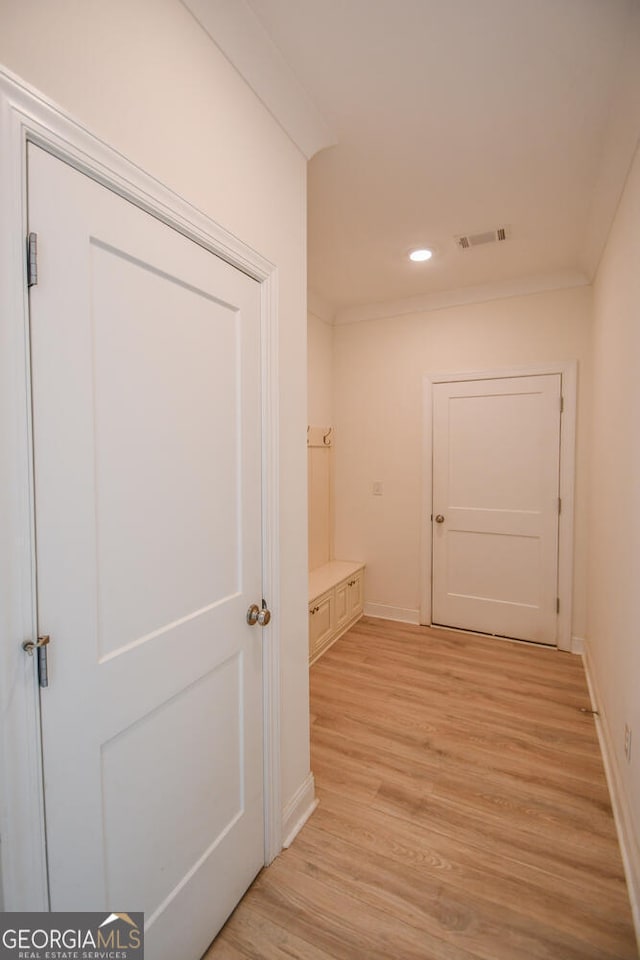hallway featuring ornamental molding and light hardwood / wood-style flooring