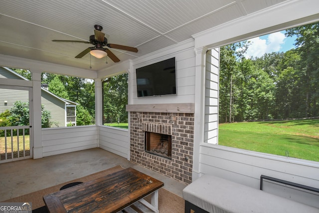 unfurnished sunroom featuring an outdoor brick fireplace and ceiling fan