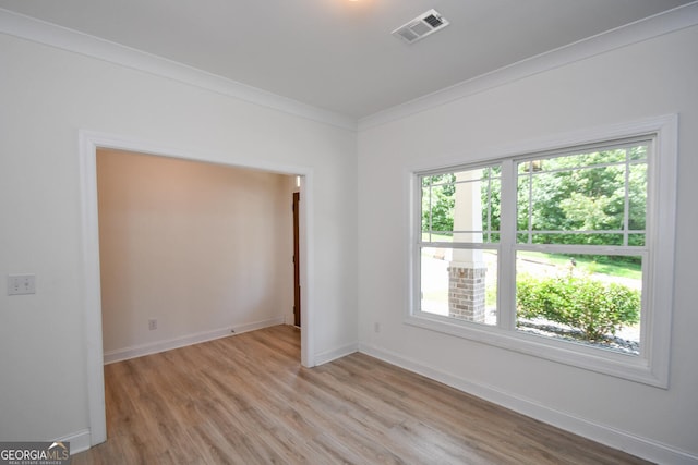 spare room with ornamental molding and light hardwood / wood-style floors