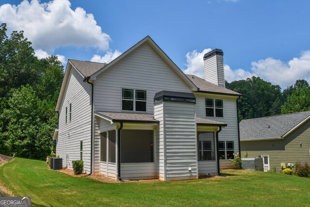 rear view of property featuring cooling unit and a lawn