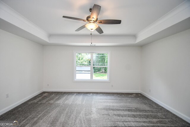 unfurnished room with a tray ceiling, dark carpet, and ceiling fan