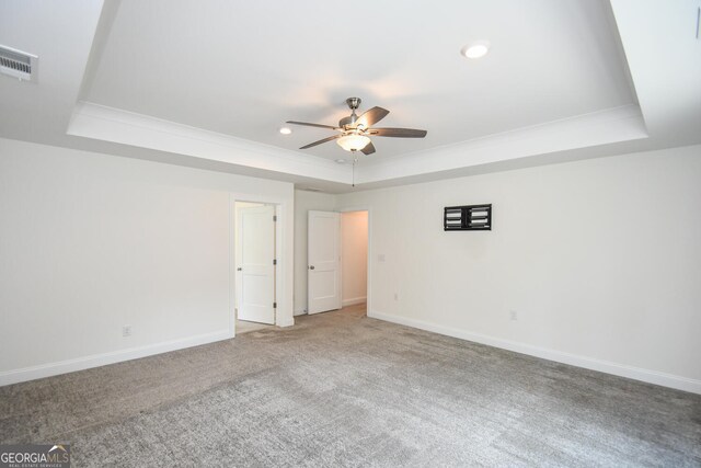 empty room featuring ceiling fan, carpet, and a tray ceiling