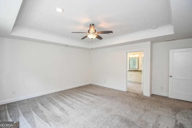 unfurnished bedroom with ceiling fan, connected bathroom, a raised ceiling, and carpet floors