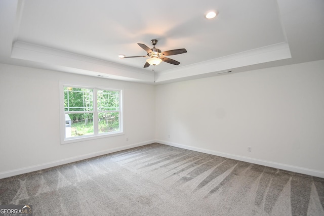 carpeted spare room featuring crown molding, a tray ceiling, and ceiling fan