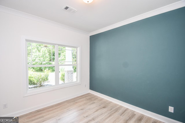empty room with crown molding and light hardwood / wood-style floors