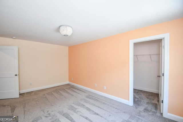 unfurnished bedroom with a walk in closet, light carpet, and a closet