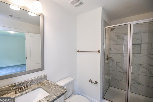 bathroom featuring a shower with door, vanity, and toilet