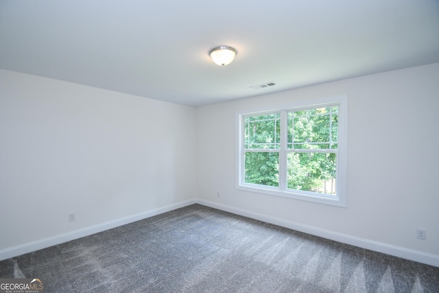 spare room featuring dark colored carpet