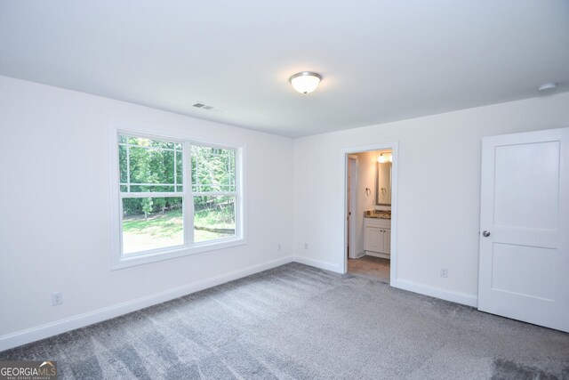 unfurnished bedroom featuring carpet floors and ensuite bath