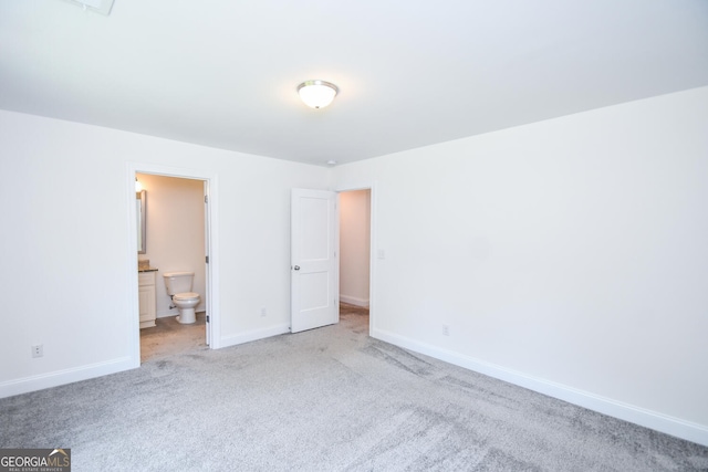 unfurnished bedroom featuring light colored carpet and ensuite bath