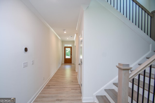 hall with crown molding and light hardwood / wood-style flooring