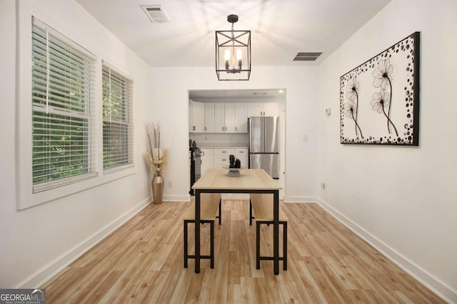 kitchen with white cabinetry, hanging light fixtures, light wood-type flooring, appliances with stainless steel finishes, and a notable chandelier