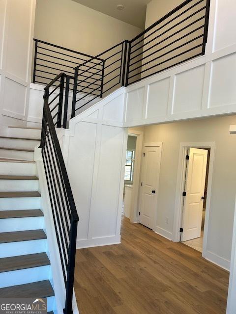 staircase featuring a towering ceiling and wood-type flooring