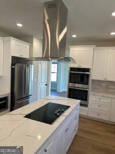 kitchen featuring island exhaust hood, decorative backsplash, stainless steel appliances, dark wood-type flooring, and white cabinets