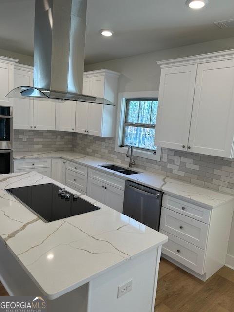 kitchen with sink, appliances with stainless steel finishes, light stone counters, white cabinetry, and extractor fan