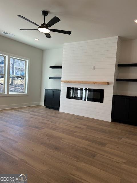 unfurnished living room featuring a fireplace, wood-type flooring, and ceiling fan