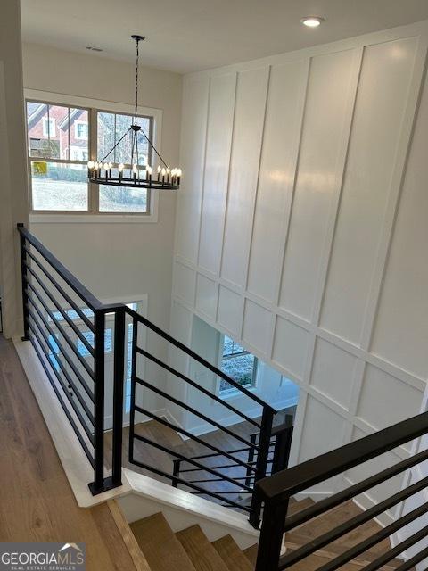 stairs with hardwood / wood-style floors and an inviting chandelier