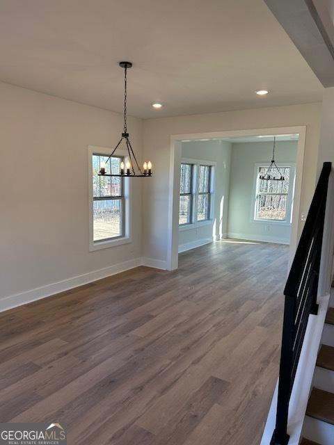 unfurnished dining area featuring plenty of natural light, wood-type flooring, and a chandelier