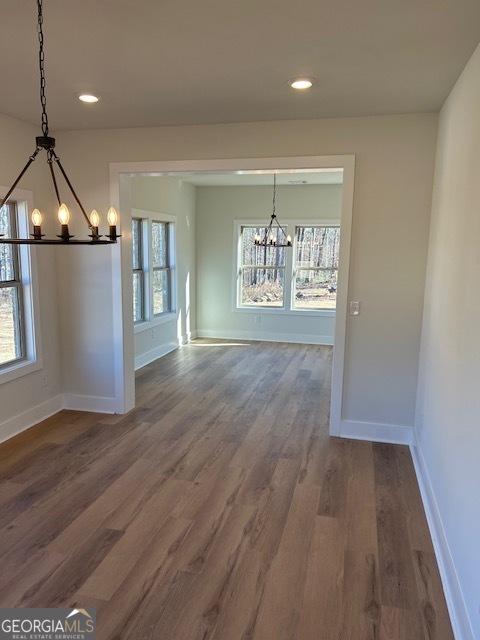 unfurnished dining area with hardwood / wood-style floors and an inviting chandelier