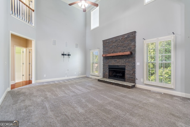 unfurnished living room with a stone fireplace, carpet, and a wealth of natural light