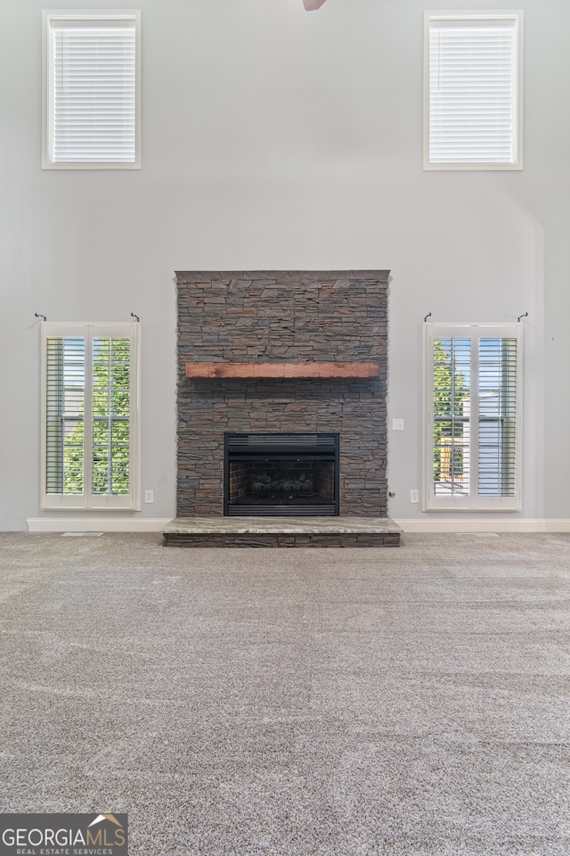 unfurnished living room featuring carpet flooring and a stone fireplace