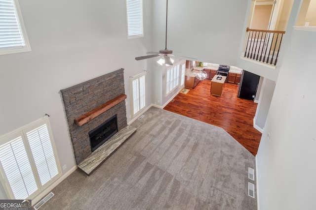 living room with a towering ceiling, a fireplace, hardwood / wood-style floors, and ceiling fan