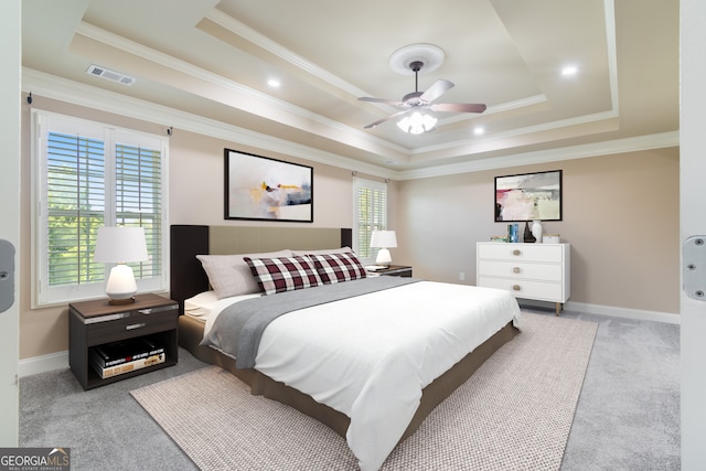 bedroom featuring light carpet, a tray ceiling, crown molding, and ceiling fan