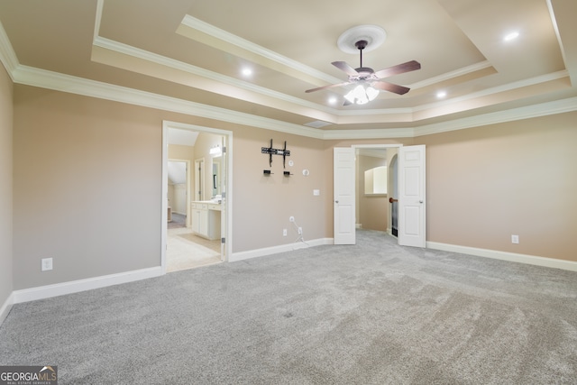 unfurnished bedroom featuring ensuite bath, crown molding, and a tray ceiling