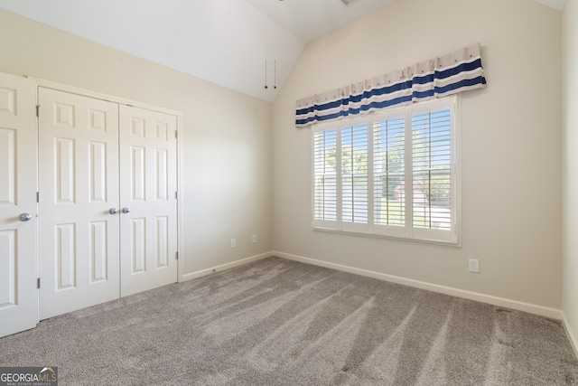 unfurnished bedroom with vaulted ceiling, a closet, and carpet floors