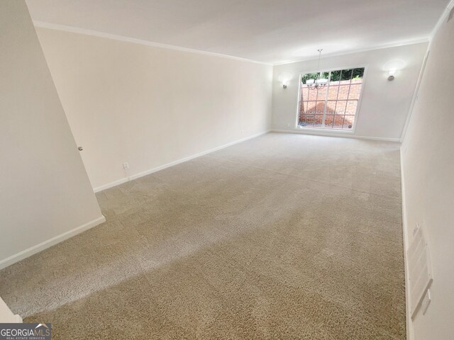 carpeted spare room with a chandelier and ornamental molding