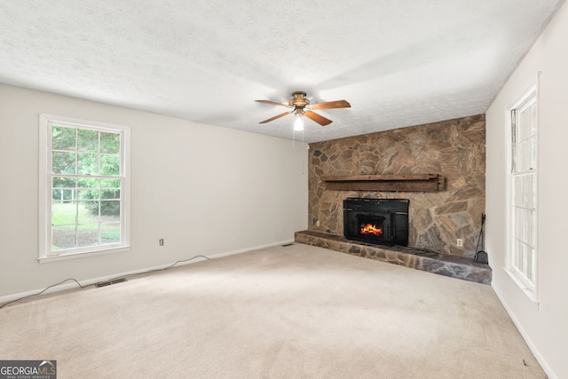 unfurnished living room with carpet, a fireplace, ceiling fan, and plenty of natural light