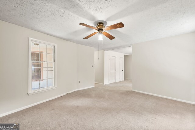 carpeted empty room featuring a textured ceiling and ceiling fan