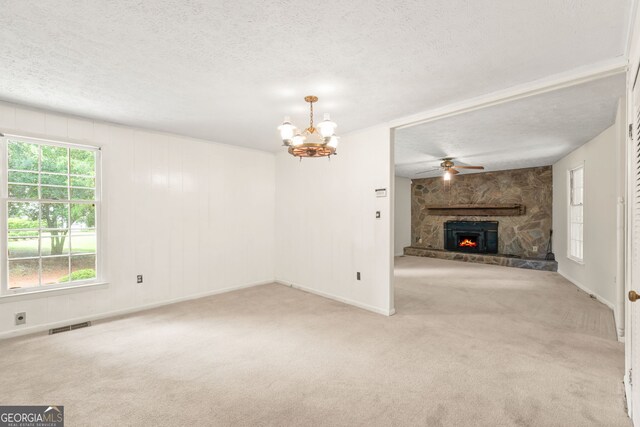 unfurnished living room with a textured ceiling, a fireplace, light colored carpet, and ceiling fan with notable chandelier