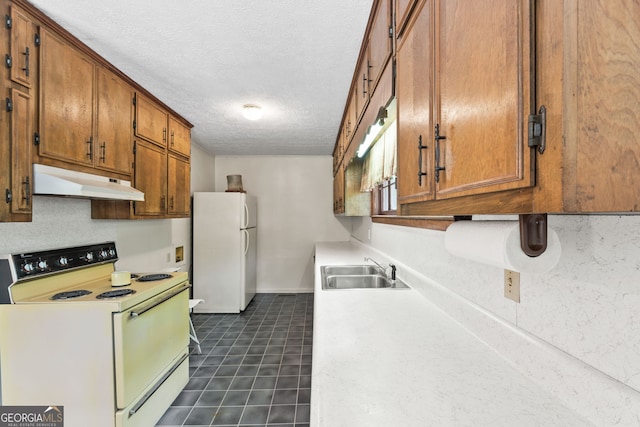 kitchen with dark tile patterned flooring, white appliances, sink, and a textured ceiling