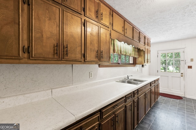 kitchen with dark tile patterned flooring, sink, and a textured ceiling