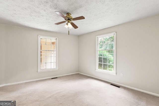 carpeted empty room featuring a textured ceiling, a healthy amount of sunlight, and ceiling fan