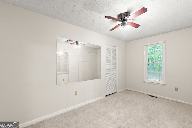 empty room featuring light colored carpet, a textured ceiling, and ceiling fan