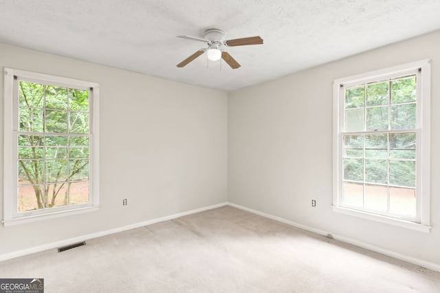 carpeted empty room with a textured ceiling, ceiling fan, and plenty of natural light