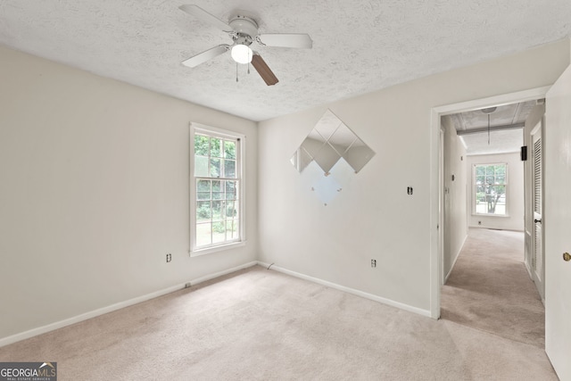 carpeted spare room with plenty of natural light, a textured ceiling, and ceiling fan