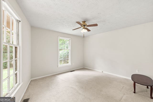 carpeted empty room featuring a textured ceiling and ceiling fan