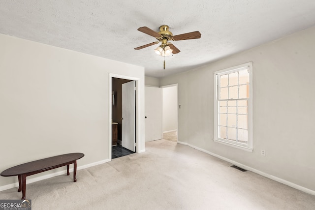 empty room featuring a textured ceiling, carpet floors, and ceiling fan