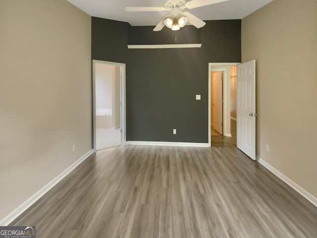 empty room featuring ceiling fan, vaulted ceiling, and light wood-type flooring