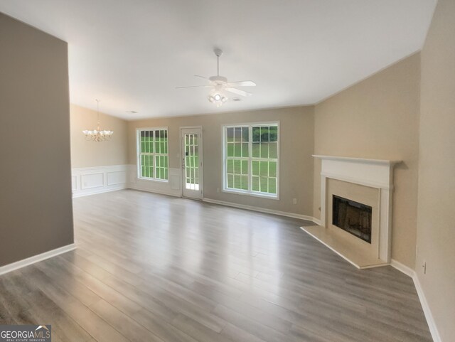 unfurnished living room featuring ceiling fan with notable chandelier, a fireplace, and hardwood / wood-style floors