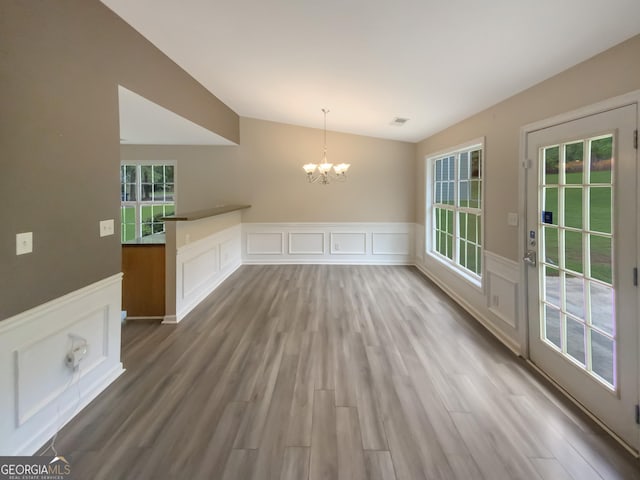 unfurnished dining area featuring wood-type flooring and a chandelier