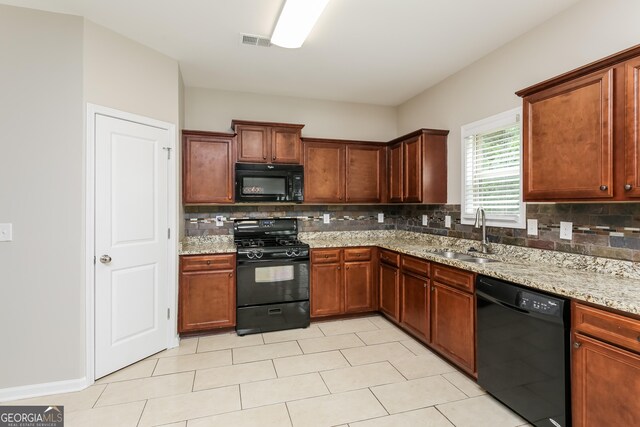 kitchen with tasteful backsplash, light tile patterned floors, light stone counters, black appliances, and sink