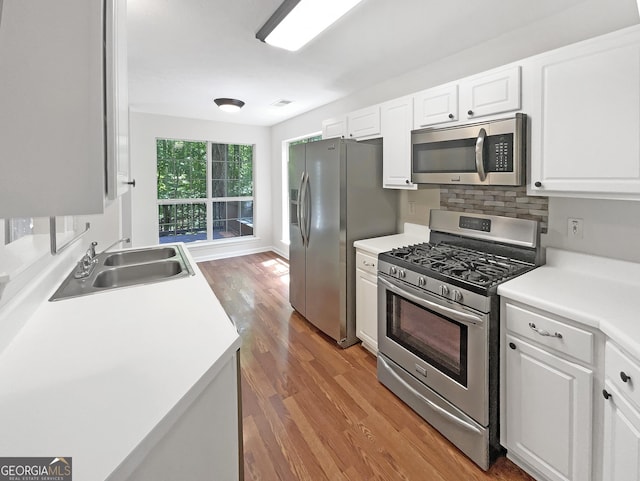 kitchen with appliances with stainless steel finishes, sink, decorative backsplash, and white cabinets