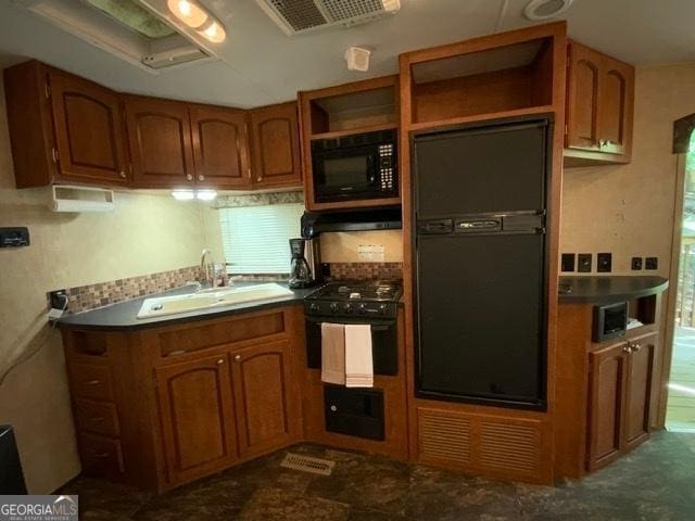 kitchen with sink, dark tile patterned flooring, and black appliances